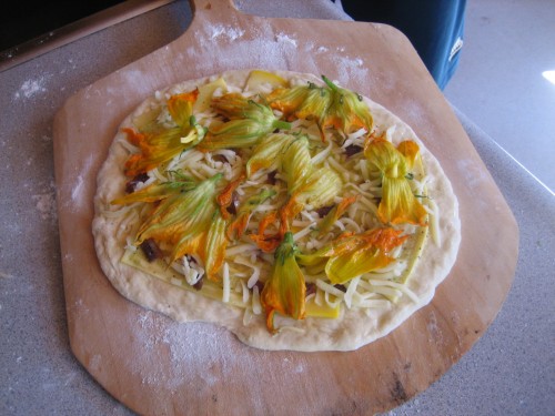 Tear the zucchini flowers apart and lay them over the pizza
